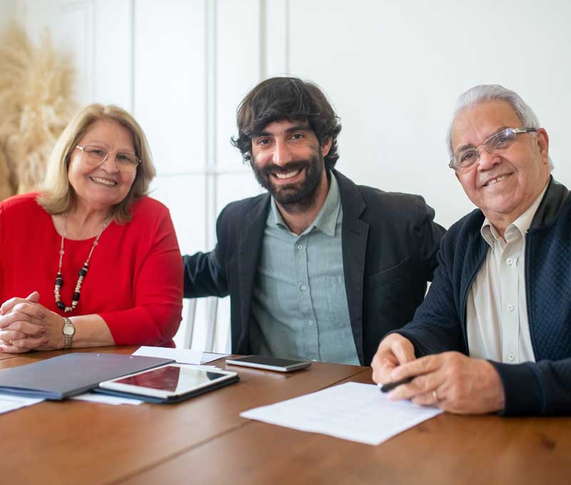 a man smiling and seated between two senior citizens