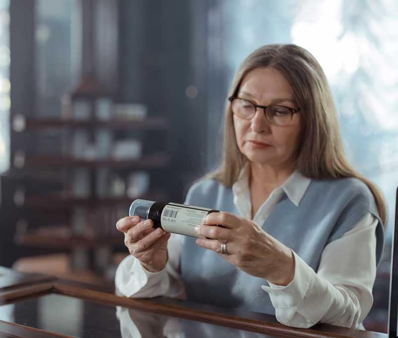 a woman reading a prescription bottle